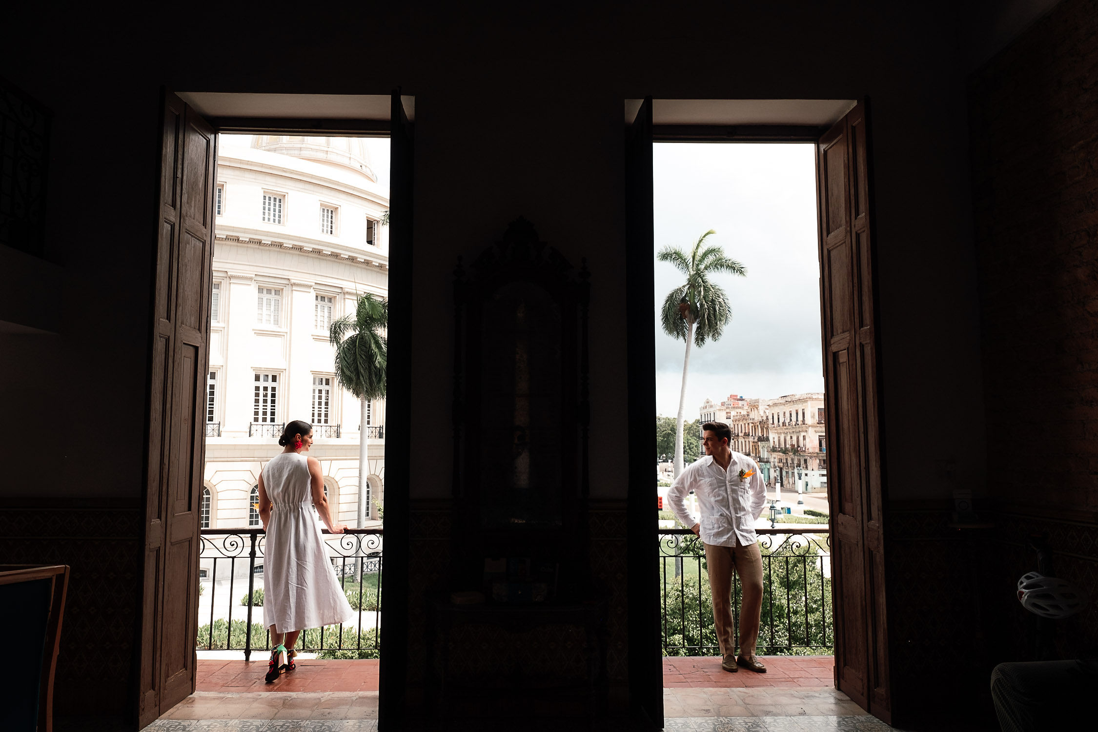 Amanda y Leo en el balcón del lugar de los preparativos con vista al Capitolio, momentos antes de su boda en La Habana, Cuba.