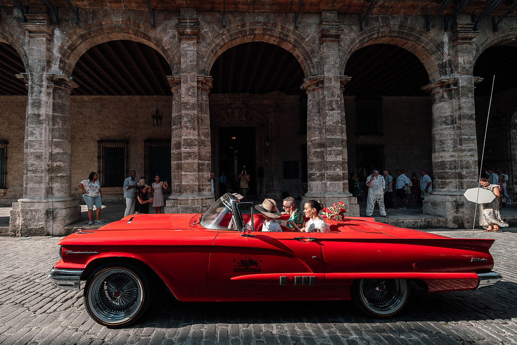 La novia llega al Palacio del Segundo Cabo en un auto clásico rojo para su boda destino cubana