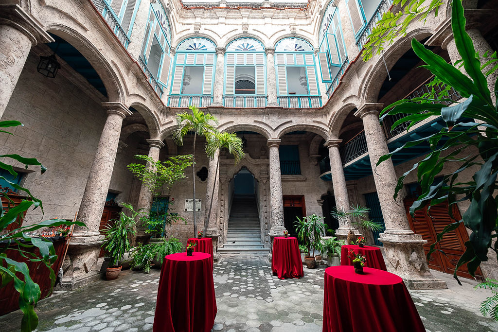 Espacio del cóctel con mesas altas y arquitectura colonial en una boda destino cubana.