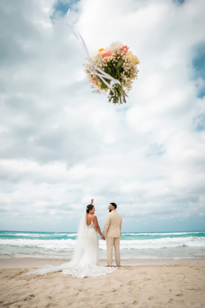 Bouquet in the foreground while the couple enjoys themselves in the background on the beach in Varadero