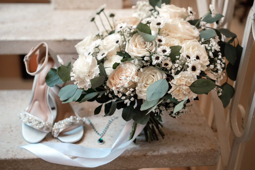 Ramo de flores blancas con accesorios de novia durante sus preparativos