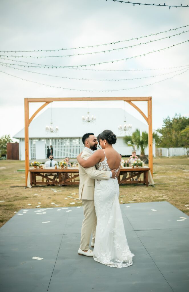 Novios bailan juntos bajo luces colgantes y cielo nocturno
