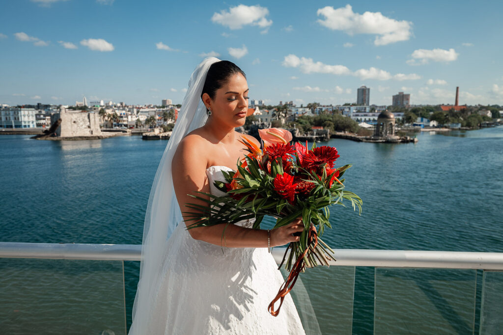 Bride on the balcony with her bouquet, city and sea view before getting married at the Hotel Nacional