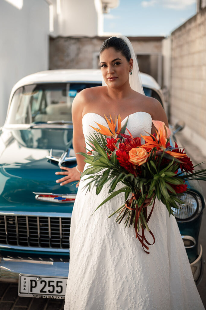 Bride ready, posing by a vintage blue car before the wedding ceremony