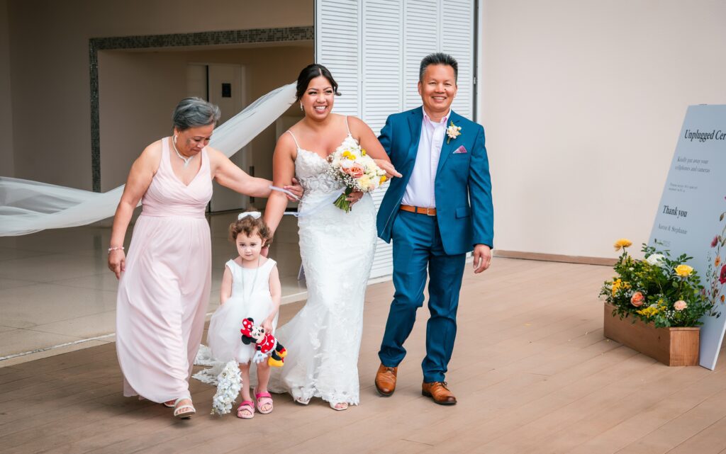 The bride walks arm in arm with her parents toward the altar