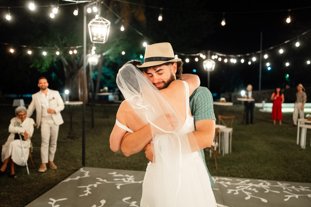 La novia abraza a un invitado que lleva uno de los sombreros de recuerdo