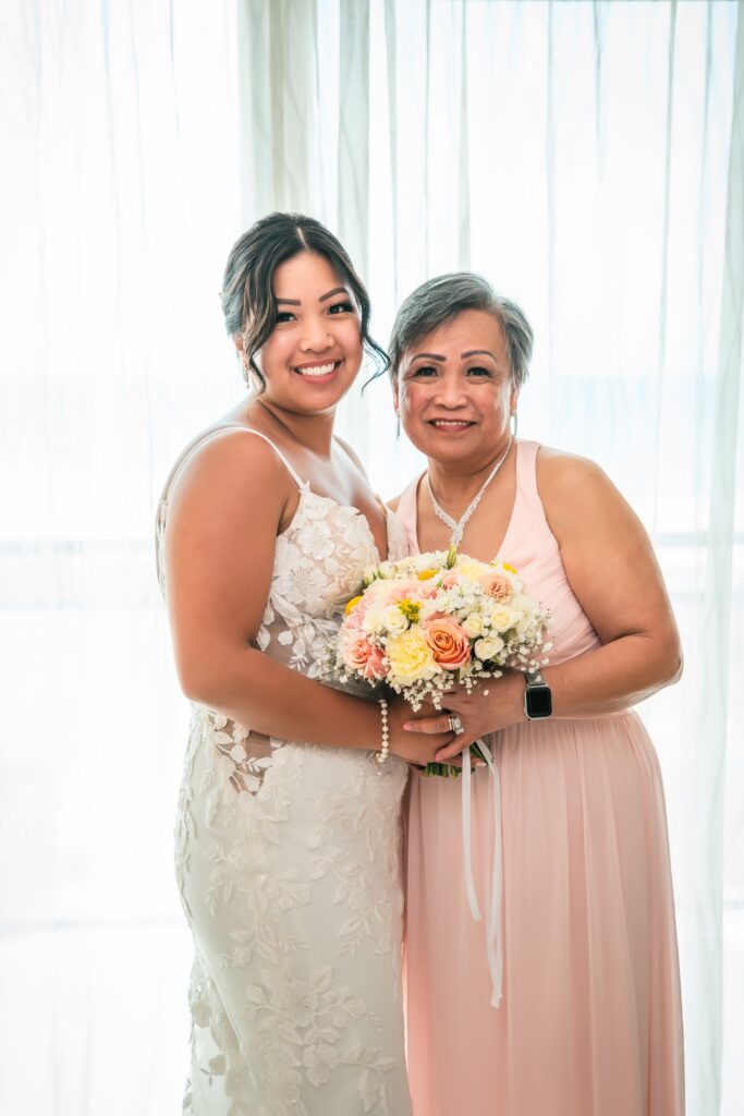 The bride and her mother embrace tenderly while holding the bouquet