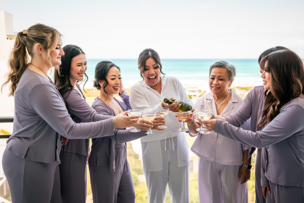 On the balcony with sea view, the bride and her bridesmaids raise their glasses