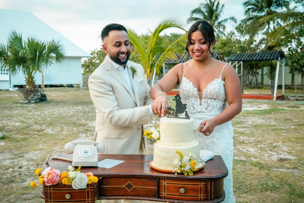 Novios cortan el pastel juntos sobre una mesa vintage decorada