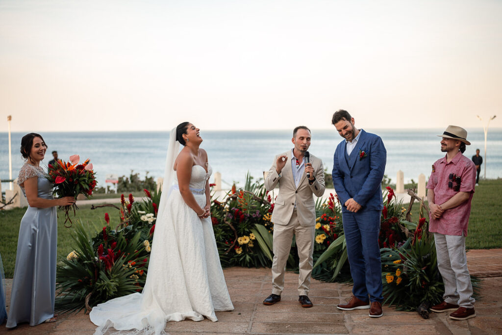 Couple in front of the officiant, surrounded by flowers and facing the sea at the Hotel Nacional