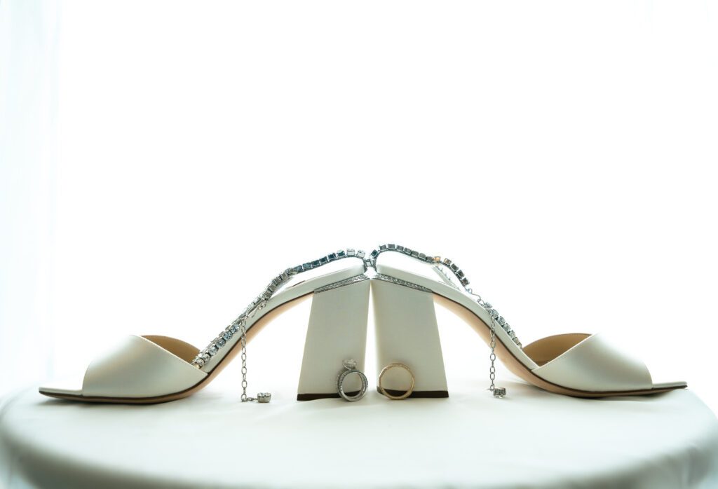 Bride’s shoes and wedding rings placed on a white background