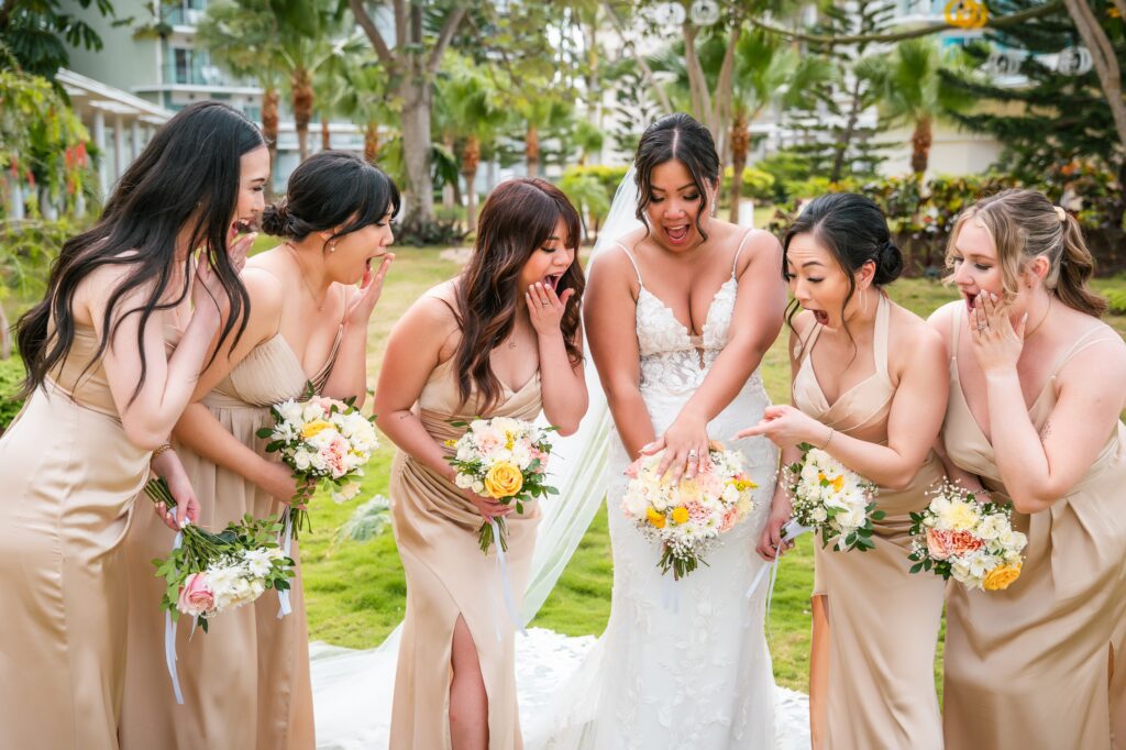 The bride and her bridesmaids pose laughing and showing their bouquets in a fun photo