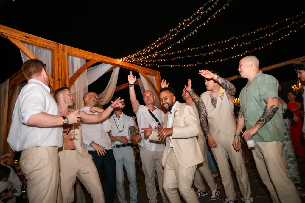 The groom dances with style and joy, joined by his friends on the dance floor