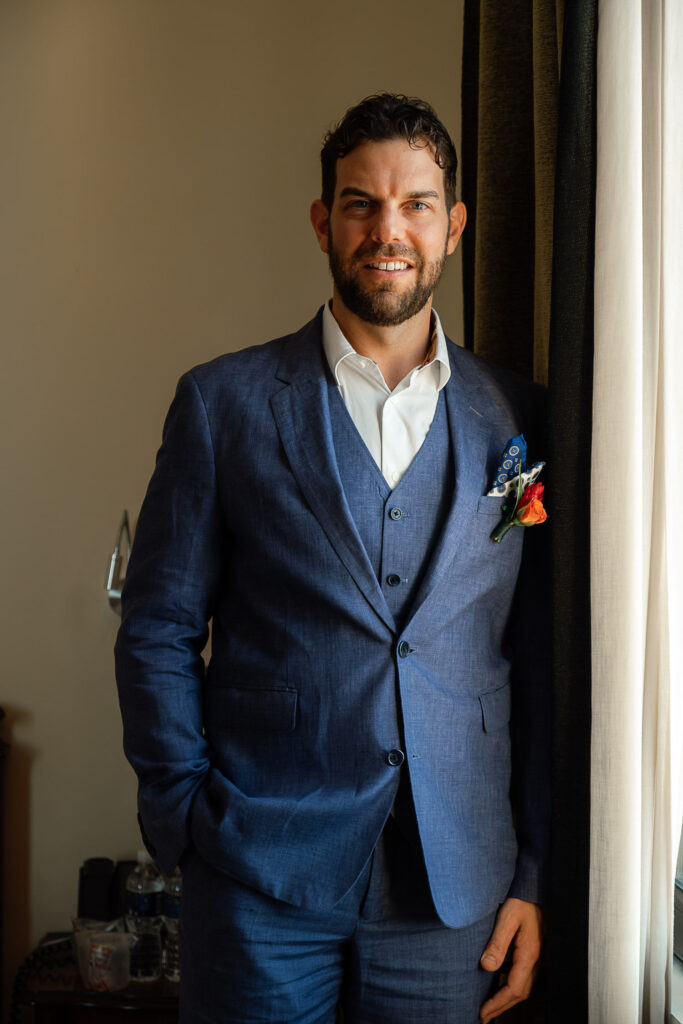 Groom standing in a blue suit during wedding preparations in Havana