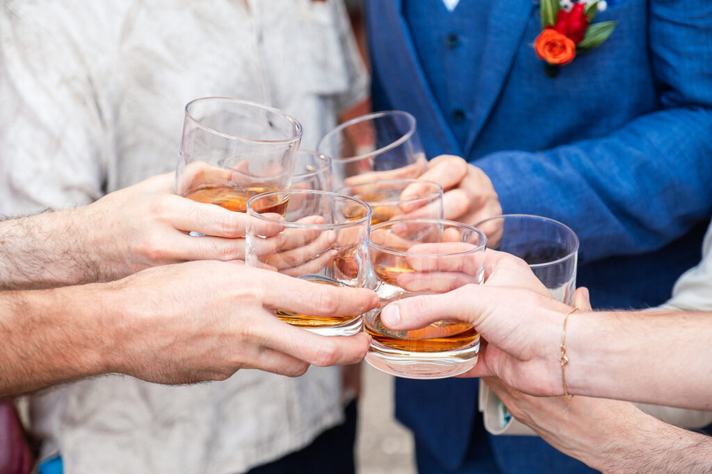 Hands and glasses in a toast by the groom and his party in the hotel gardens before the ceremony