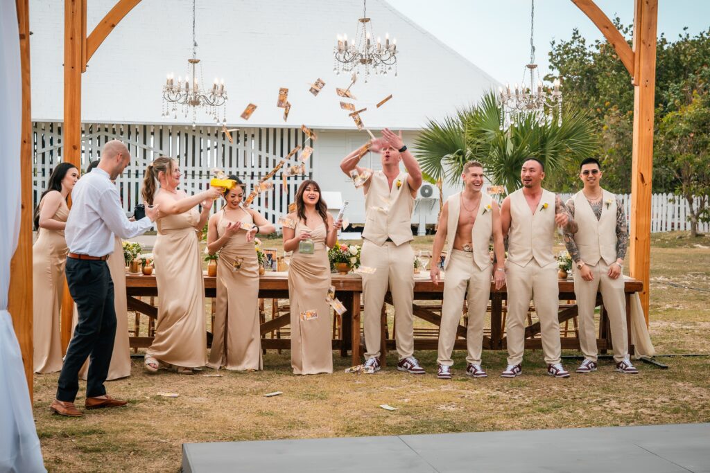Groomsmen and bridesmaids wait at the head table during the wedding in Varadero while tossing play money.