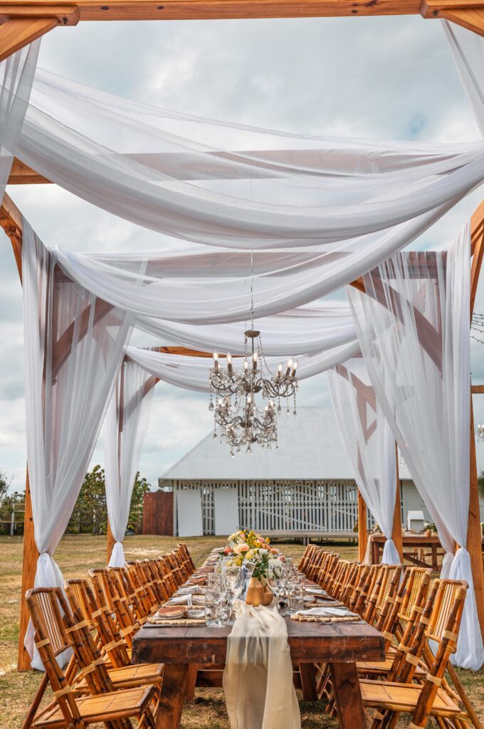 Mesa larga decorada con telas vaporosas y chandeliers en la recepción