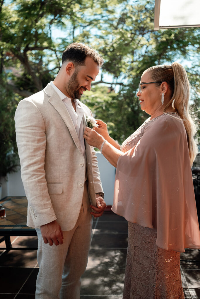 La madre coloca el ramillete al novio durante los preparativos de la boda en Cuba
