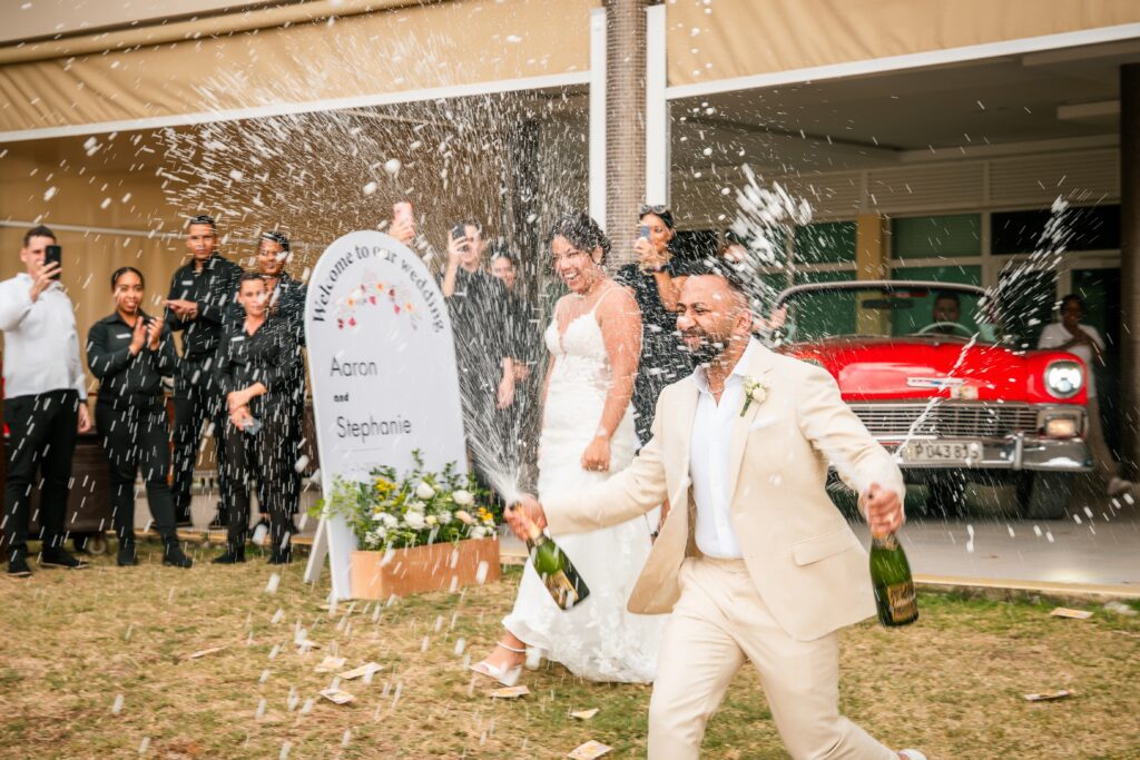 The couple enters the wedding dinner in Varadero carrying bottles of champagne.