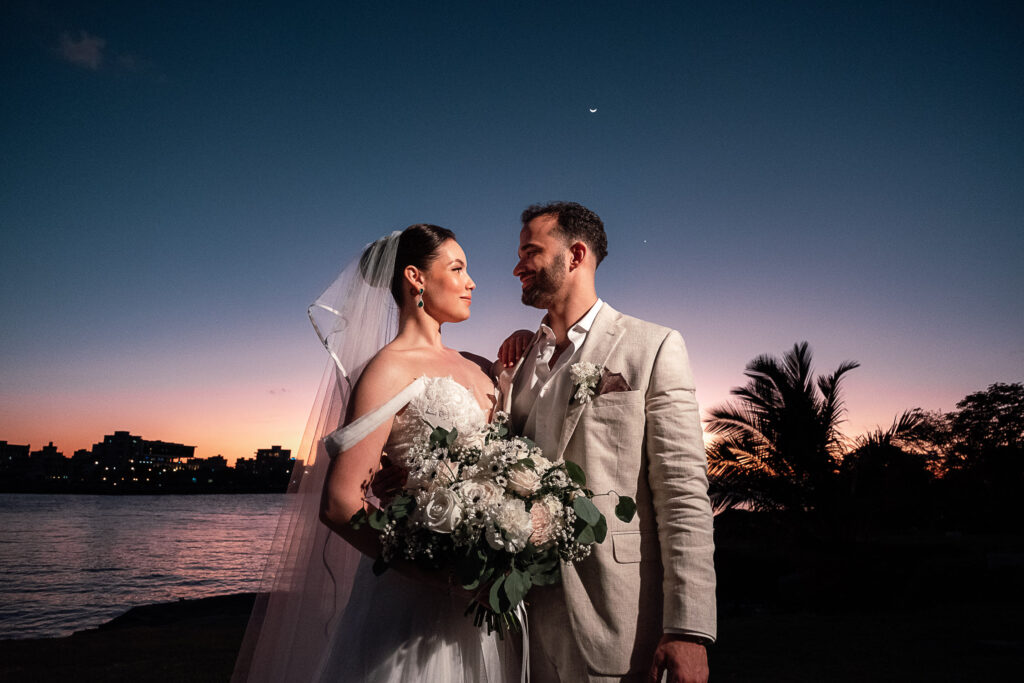 Novios posando al atardecer con la ciudad y el mar de La Habana como fondo