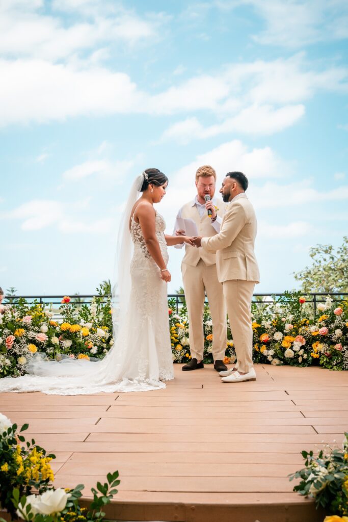 The couple exchange vows under a floral arch during the ceremony