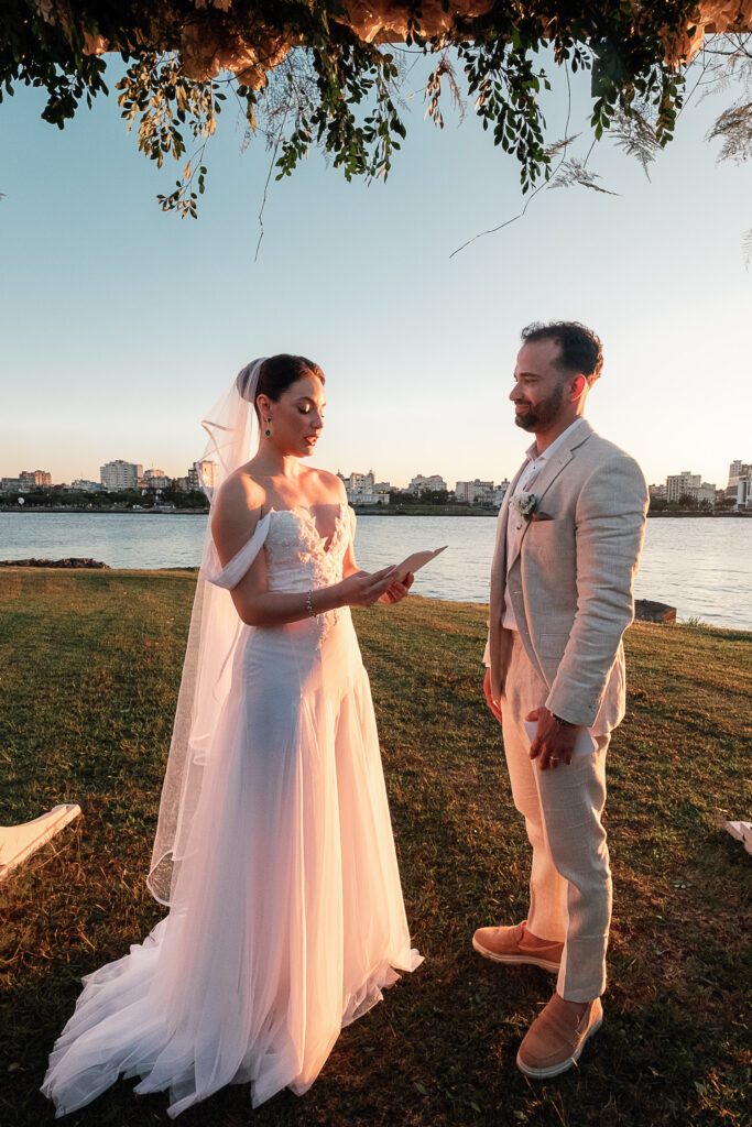 Novia lee sus votos en el gazebo decorado con flores blancas junto al mar en Cuba