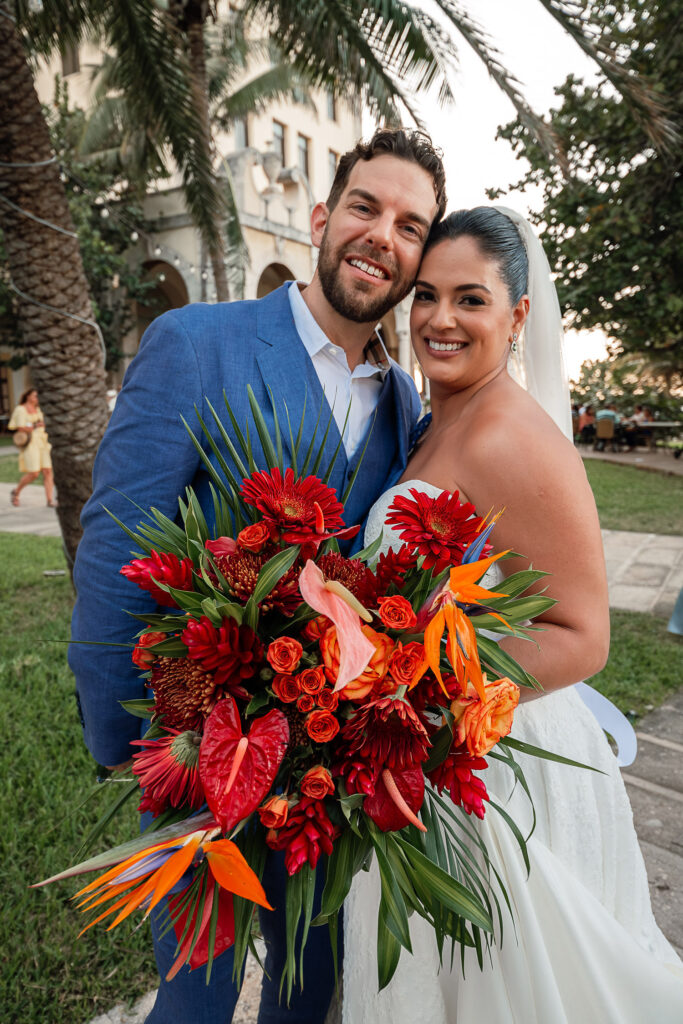 Couple posing with the Hotel Nacional in the background and the bouquet centered in the shot