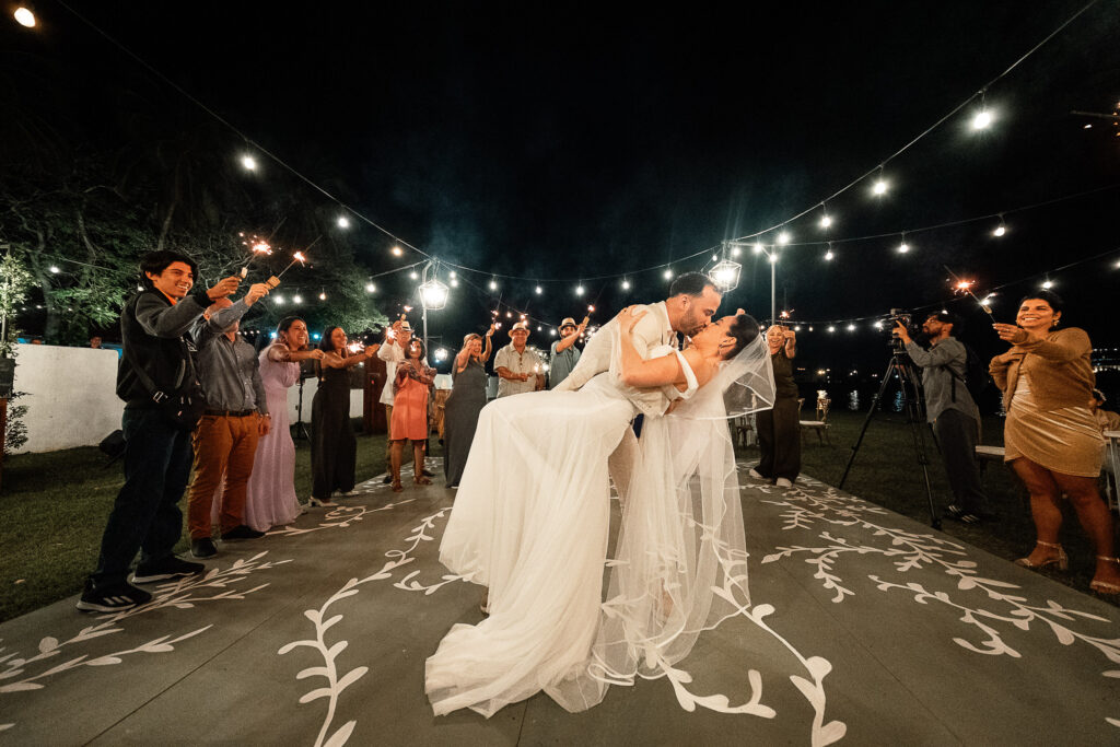 Novios se besan en la pista de baile rodeados de invitados celebrando