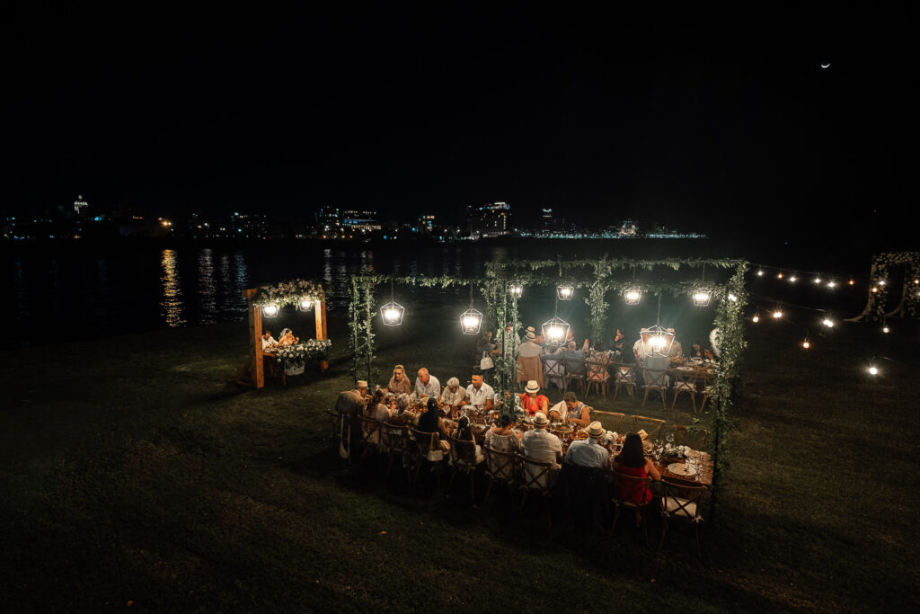 Vista aérea de la cena con novios e invitados, decoración floral y faroles cálidos