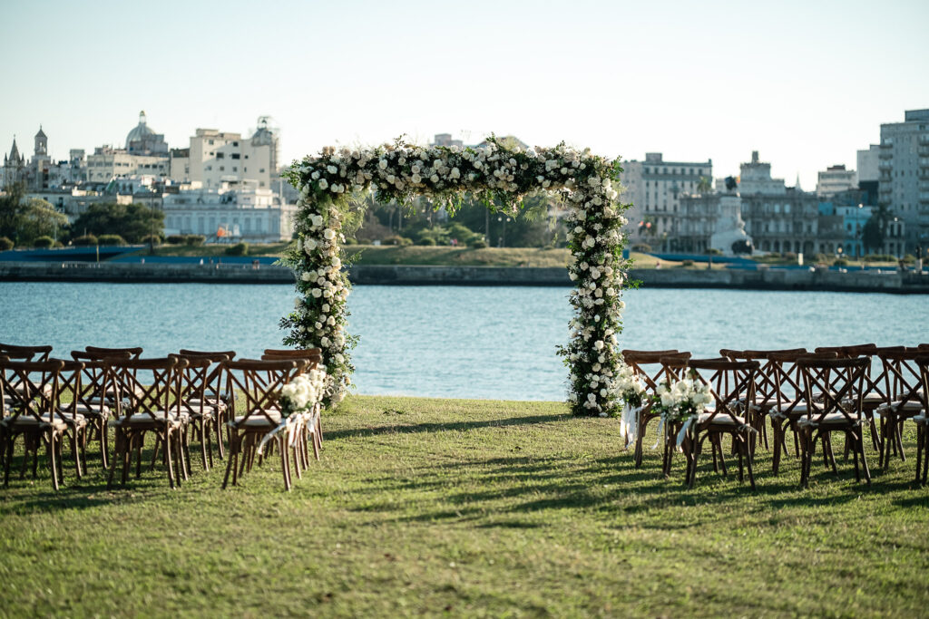 Gazebo con flores blancas y sillas de invitados frente al mar en Cuba
