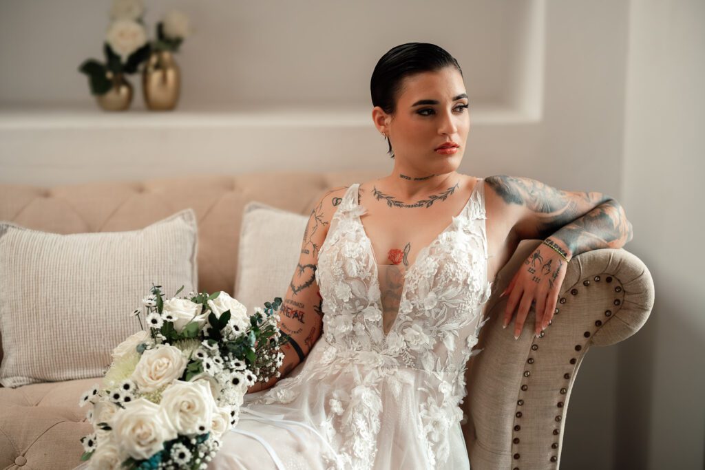 Tattooed bride with white bouquet, seated before the wedding ceremony in Cuba under the most beautiful dome