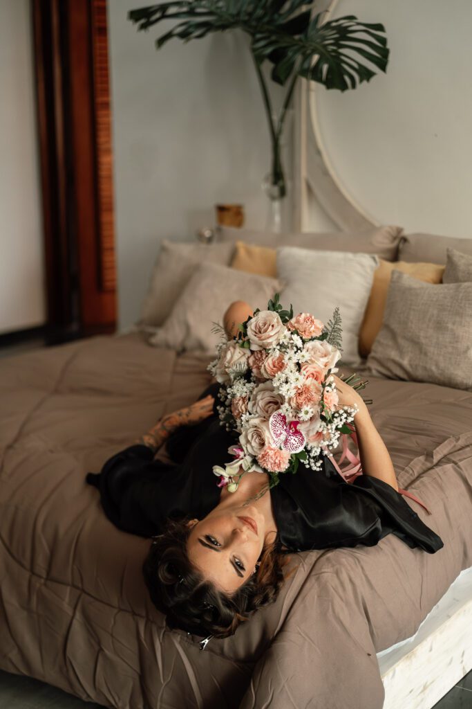 Bride lying on the bed with a pink-toned flower bouquet before the wedding in Cuba under the most beautiful dome