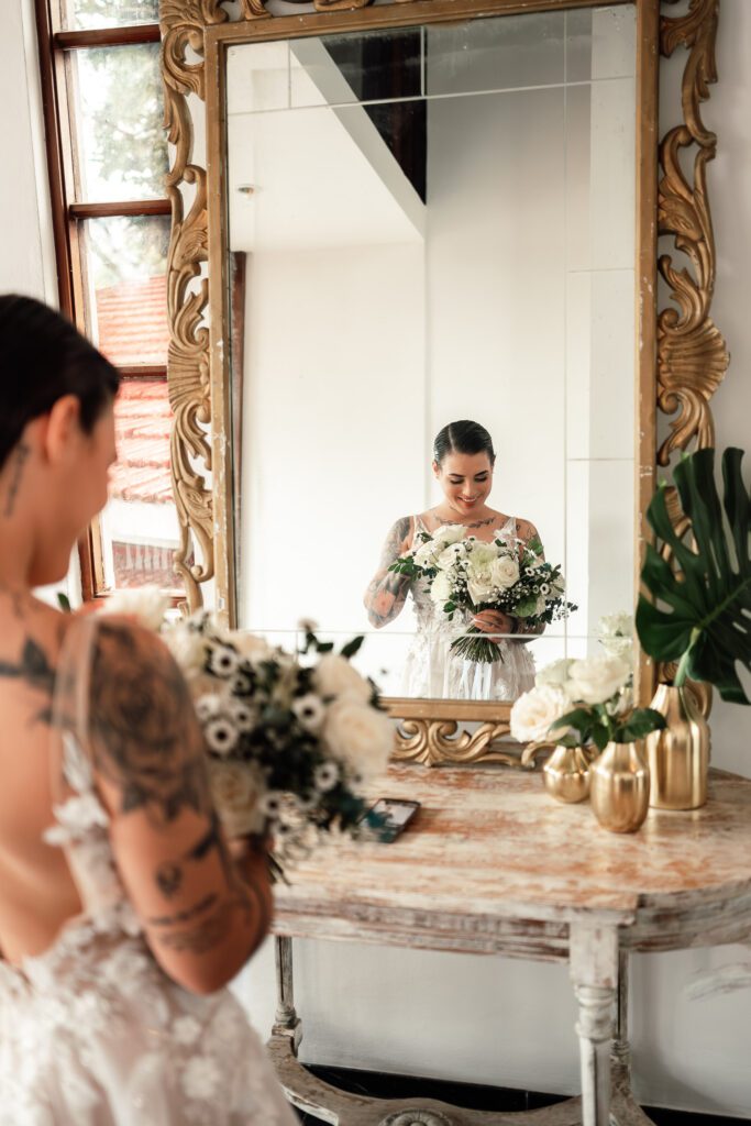 Reflection of the bride in the mirror holding her white bouquet before the wedding