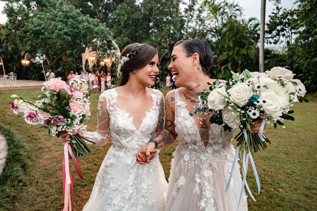The brides walk hand in hand, laughing, after their ceremony in Cuba