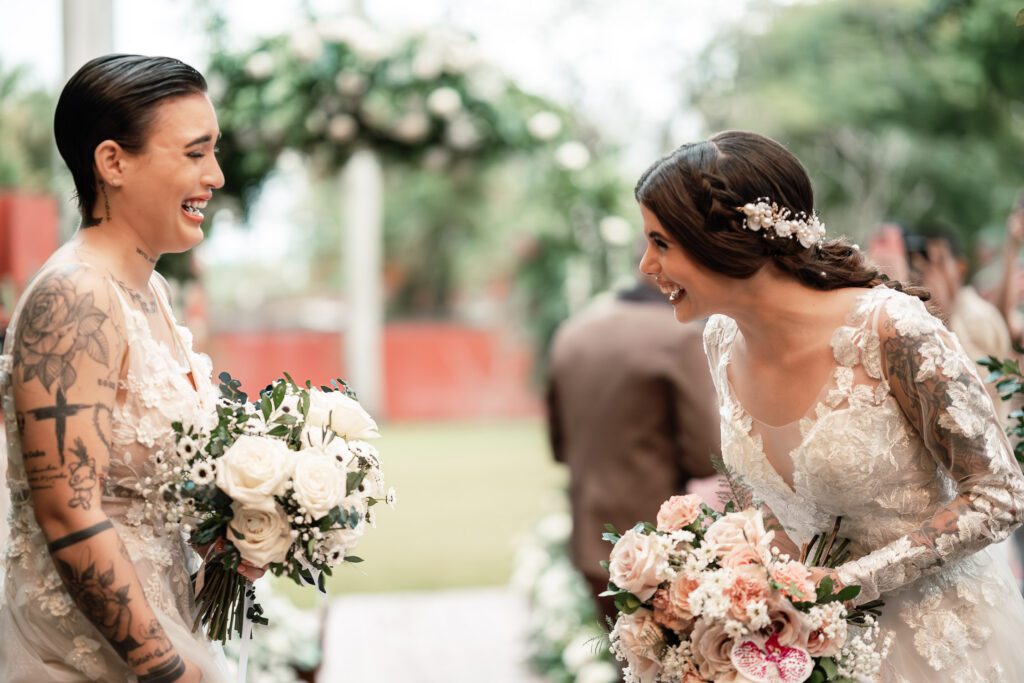 Brides laugh as they look at each other, holding their bouquets after the wedding ceremony in Cuba under the most beautiful dome
