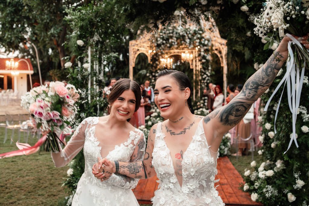 The brides raise their arms as they exit their wedding in Cuba under the most beautiful dome
