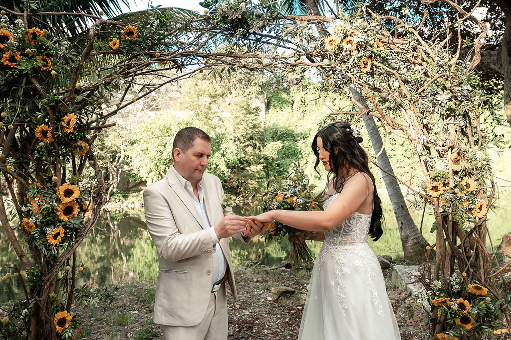 Couple exchanging rings during their ceremony, surrounded by the greenery of Havana’s forest.