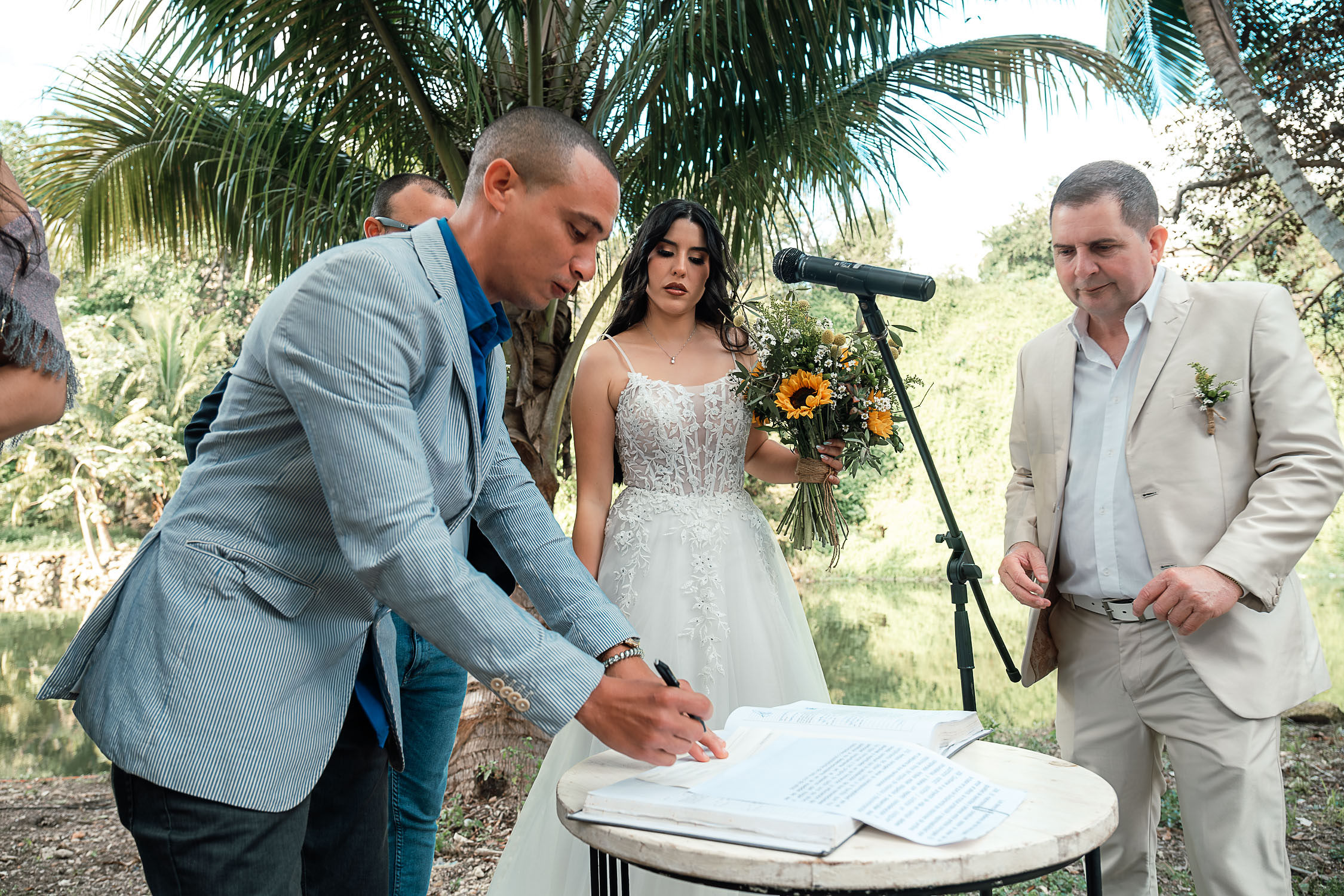Bride signing the marriage certificate during her civil wedding in Cuba, in the middle of the Havana Forest, alongside the groom and the notary.
