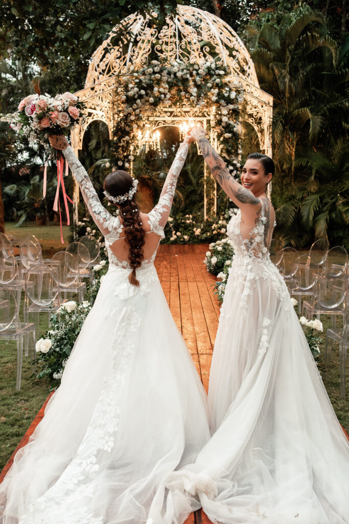 Noivas levantam os braços em celebração após a cerimônia de casamento gay em Cuba.