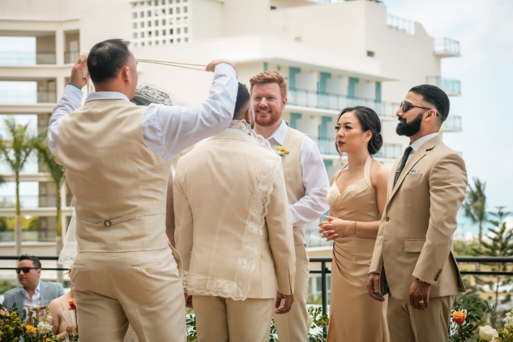 One of the groomsmen gets ready to place the wedding cord over the couple during the ceremony