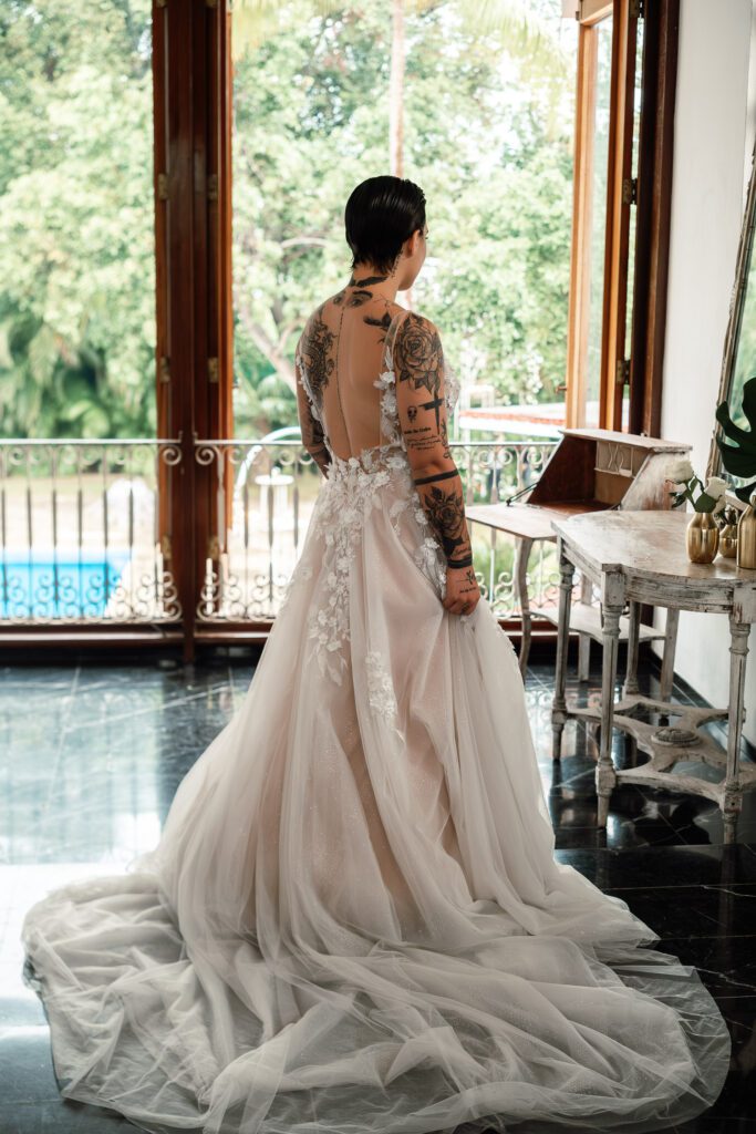 Full view of the dress with a train and visible tattoos on the bride’s back
