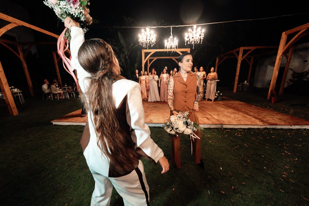 One of the brides gets ready to toss the bouquet while the other watches playfully