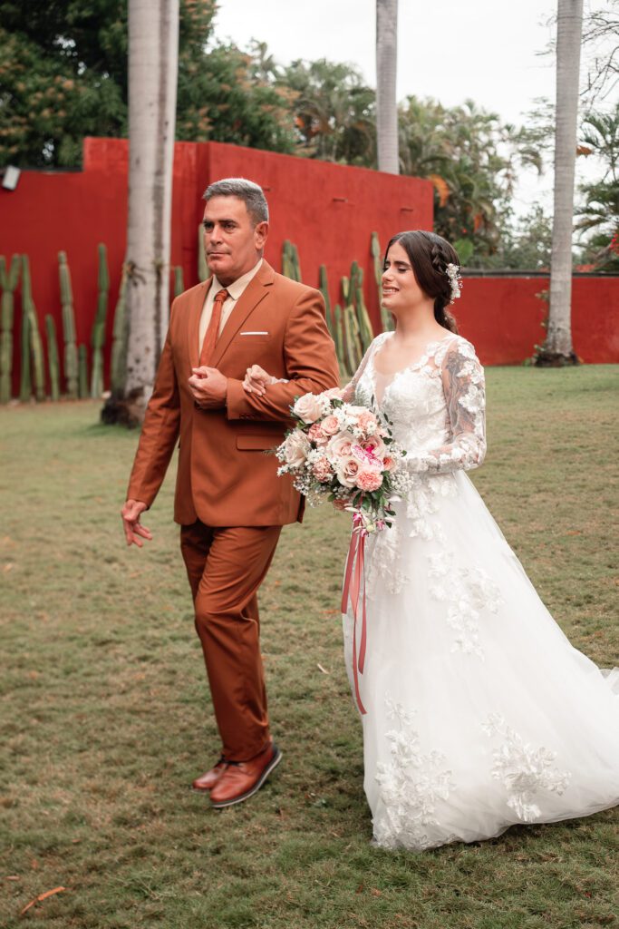 Gabriela arrives at the ceremony on her father’s arm during her wedding in Cuba under the most beautiful dome