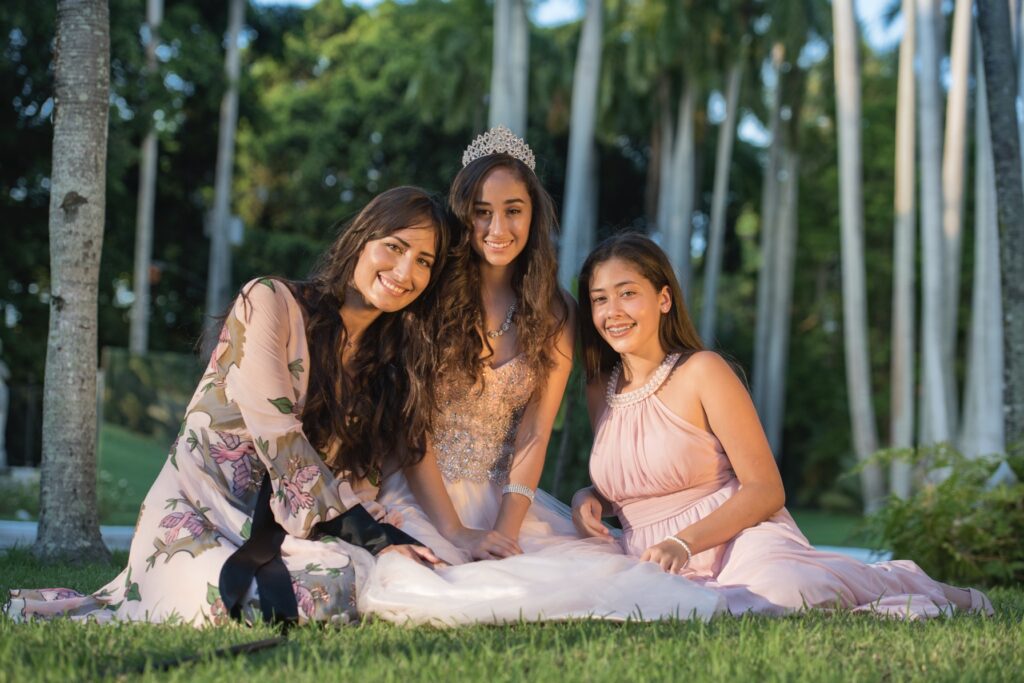 Familiares sentadas en el césped rodeadas de palmas y vegetación en un jardín durante una fiesta de 15 años en La Habana