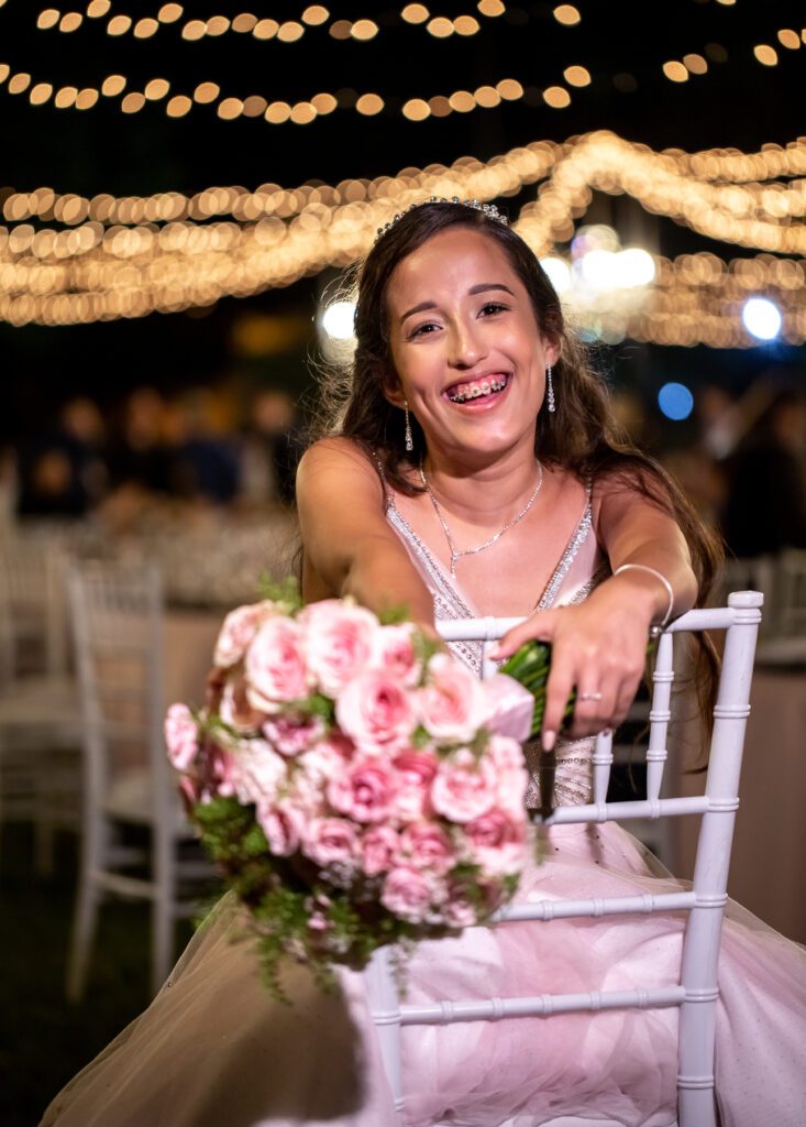 Quinceañera mostrando un ramo de flores regalado por sus padres durante su fiesta en La Divina Pastora