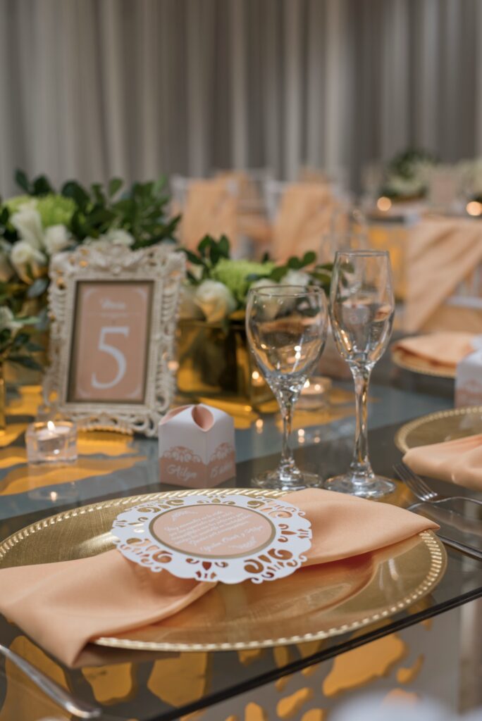 Decoración de mesa en fiesta de quince años con servilleta melocotón y bajo plato dorado