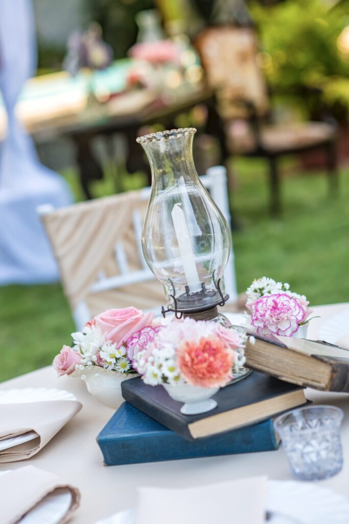 Centro de mesa con quinqué antiguo, flores frescas y libros en una fiesta de quince