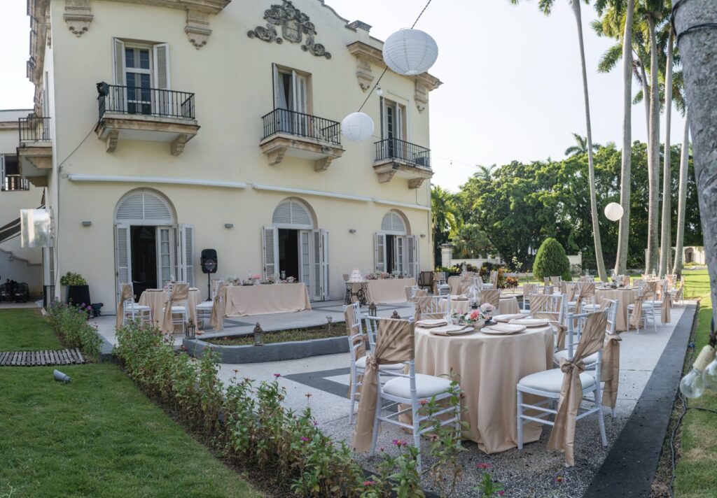 Vista exterior del jardín y terraza decorados para una fiesta de quinceañera con mesas y sillas arregladas en tonos champán