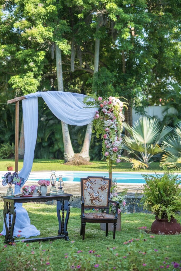 Arco decorado con flores y tela blanca en un jardín para una fiesta de quinceañera vintage