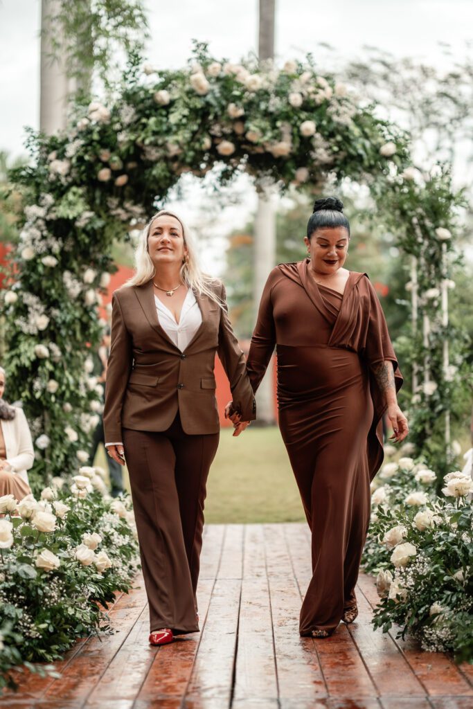 Two elegant women walking hand in hand at the entrance to the ceremony